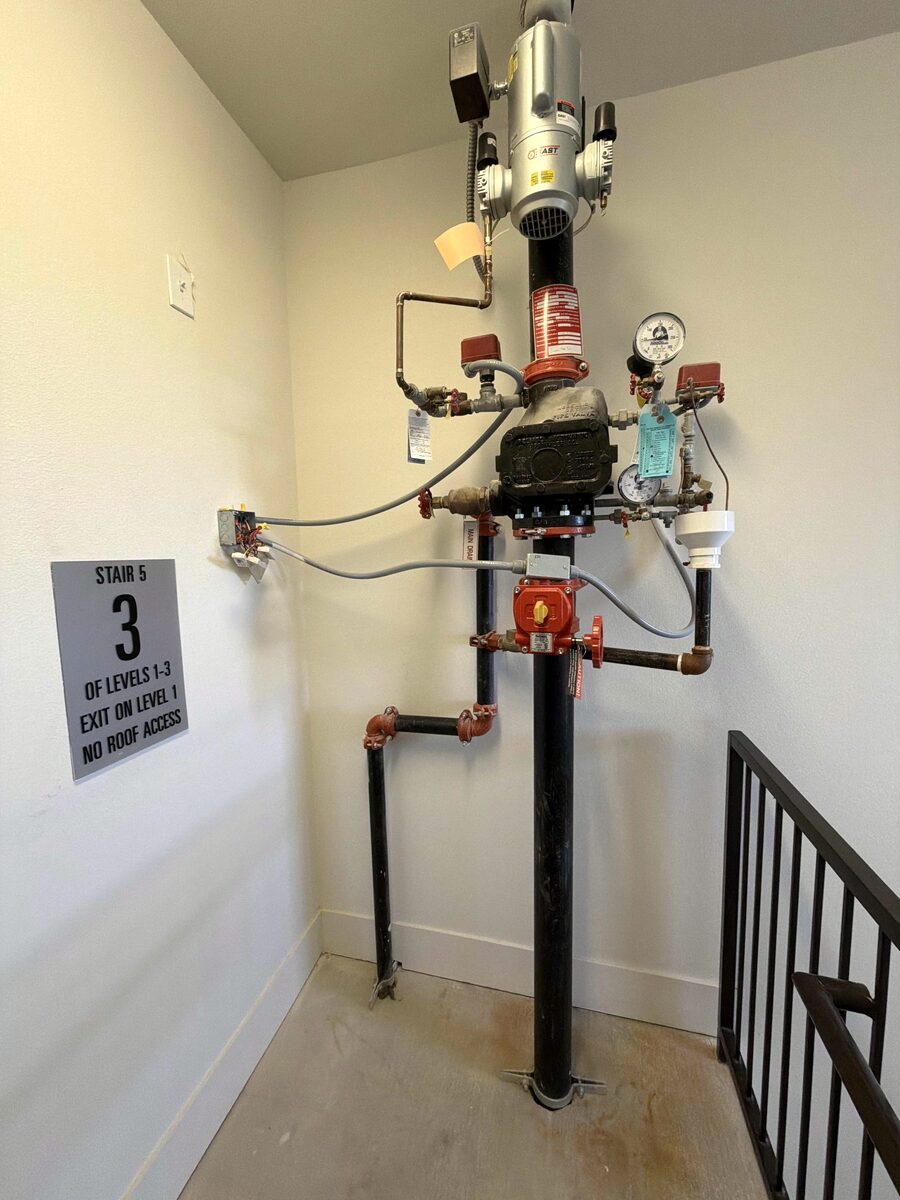 Sprinkler floor control assembly in an apartment building stairwell, with the stair sign on the wall beside it