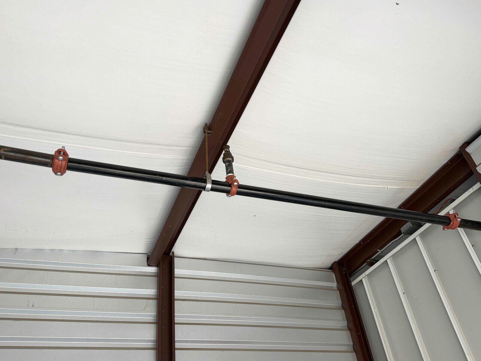 New fire sprinkler pipe and fittings installed inside a storage unit after Paragon's repair, all joints clean and supported