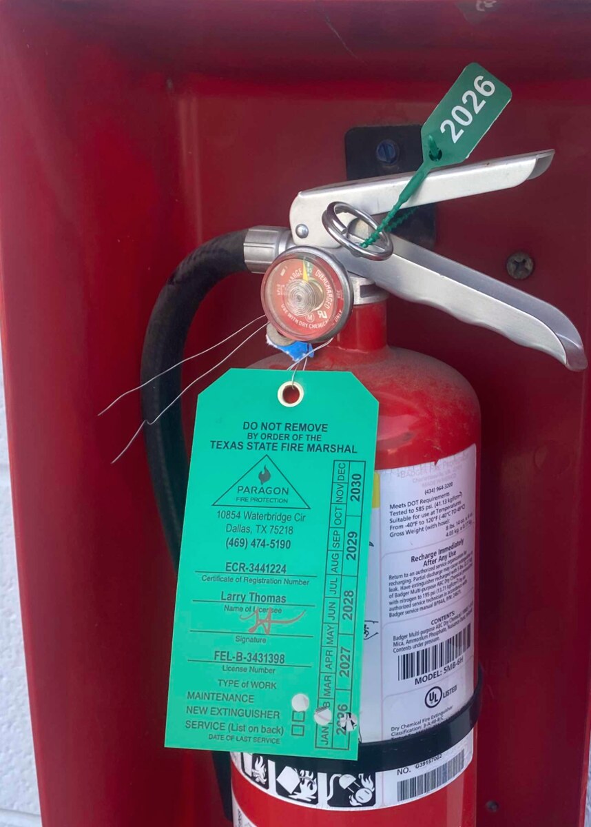 After: Extinguisher — gauge below the green band at annual visual → recharged, weighed, sealed, and re-tagged at the Paragon shop.