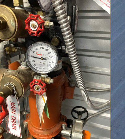 Riser-room gauges reading at-spec after the repair; main-drain tag in place